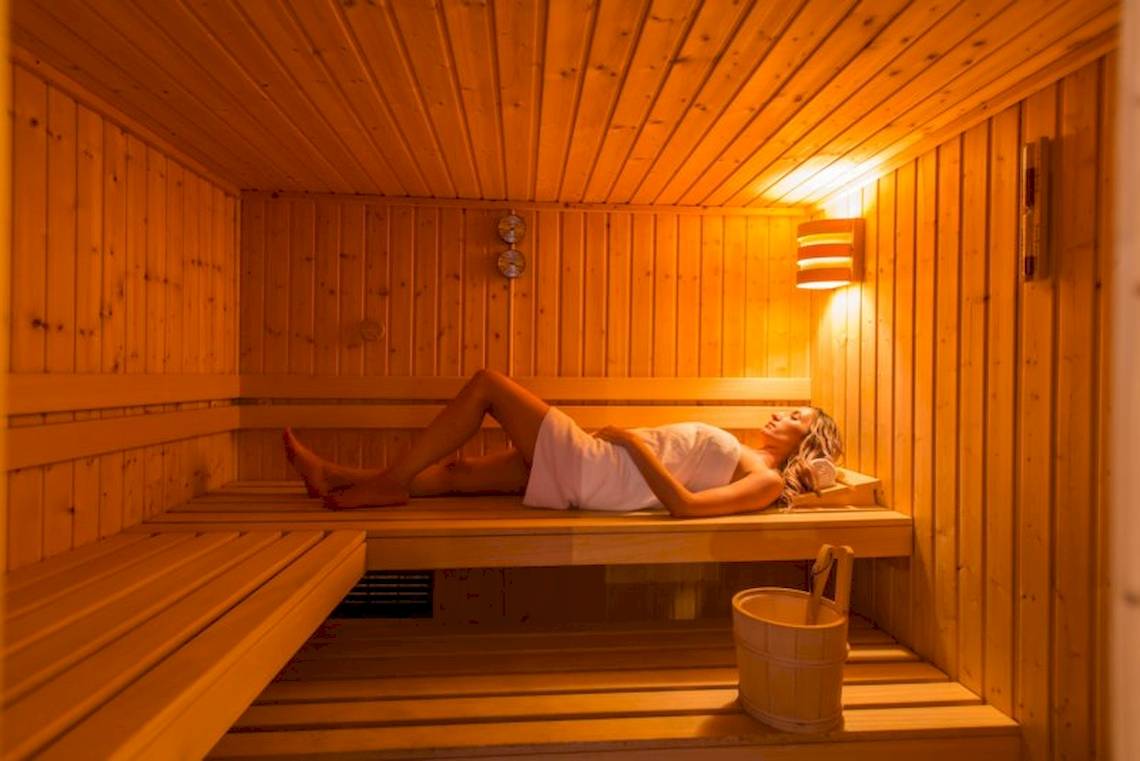 Frau liegt entspannt in einer Holzsauna