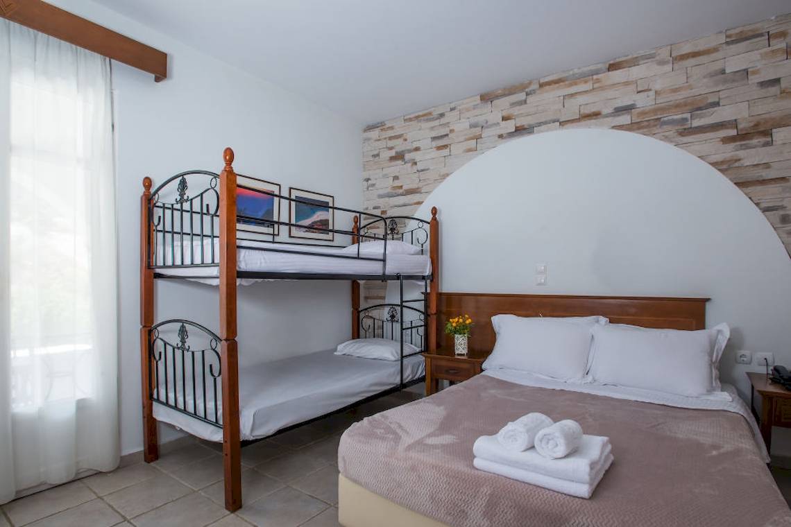 Schlafzimmer mit Doppelstockbett und Bett, beide mit weißen Laken und Kissen.