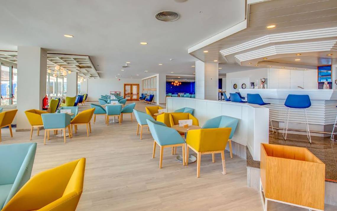 Innenansicht des SBH Maxorata Resorts mit farbenfrohen Stühlen und Tischen, einer Bar und Panoramafenstern.