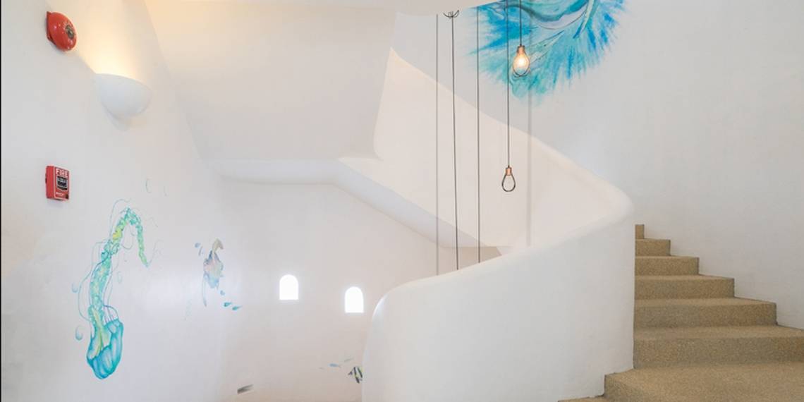 Innenansicht des Ocean Breeze Resort Khao Lak mit einer Wendeltreppe und Wandmalereien.