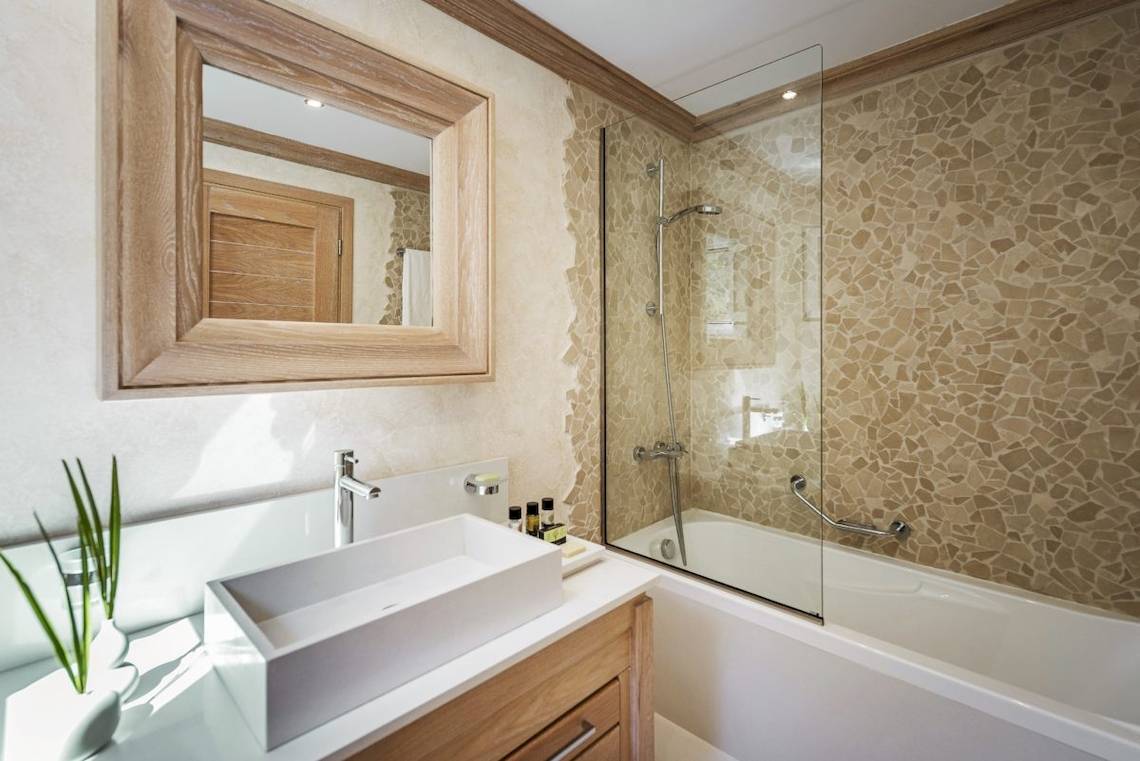 Badezimmer im Mitsis Rodos Village Beach Hotel & Spa mit Badewanne, Waschbecken und Spiegel.