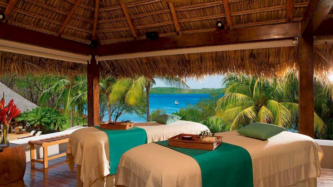Zwei Massageliegen im Freien mit Blick auf das Meer am Secrets Papagayo Costa Rica Hotel.
