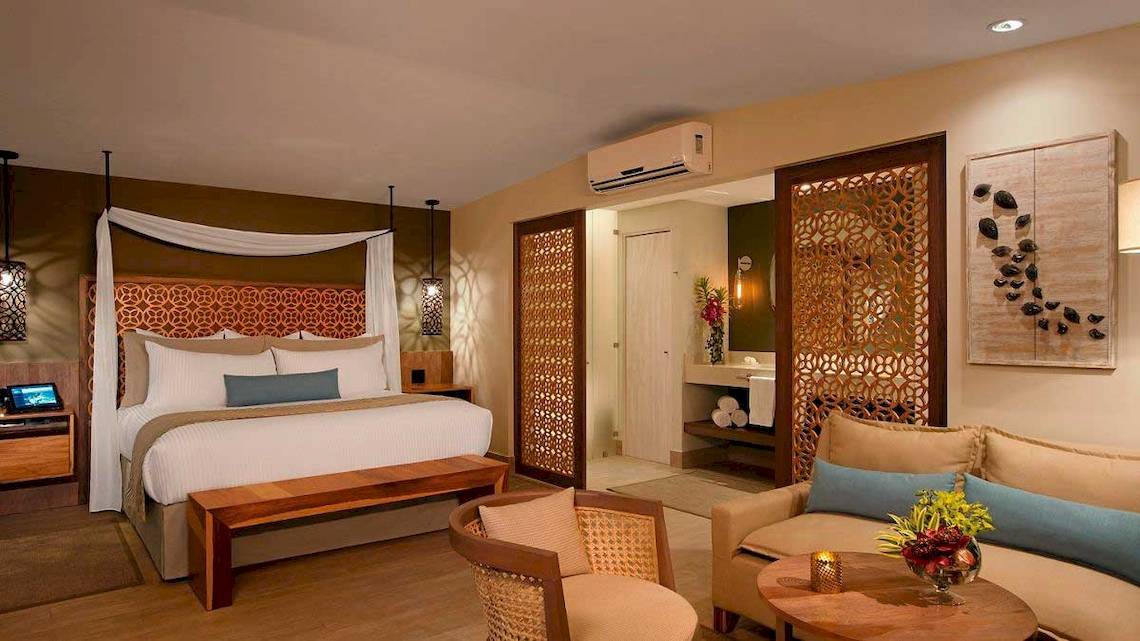 Suite im Secrets Papagayo Costa Rica mit Doppelbett, Wohnzimmerbereich und modernem Dekor.