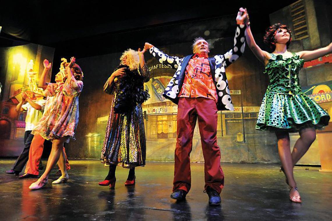 Schauspieler des Hotels Nirvana Dolce Vita auf der Bühne in farbenfrohen Kostümen.