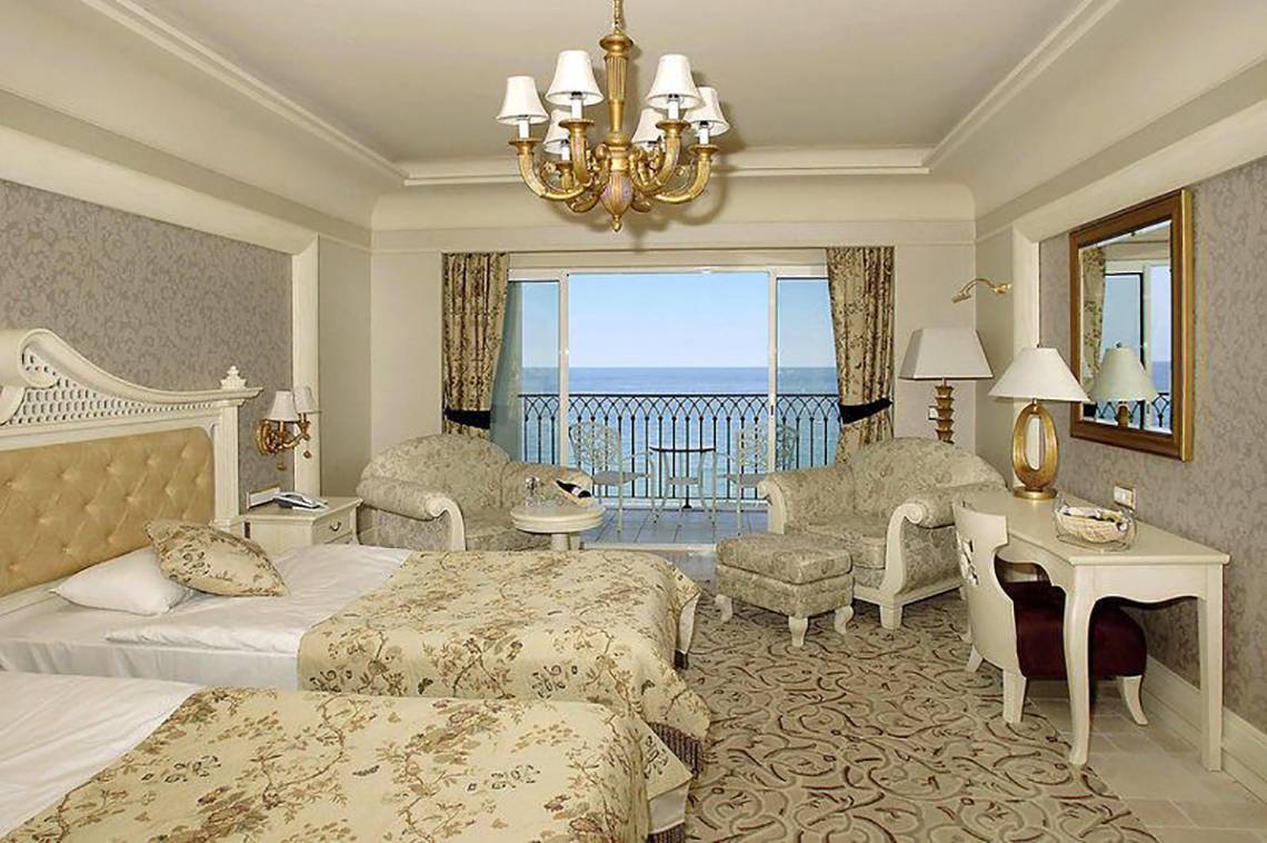 Doppelzimmer mit Meerblick im Hotel Nirvana Dolce Vita mit zwei Betten, einem Schreibtisch und einem Balkon.