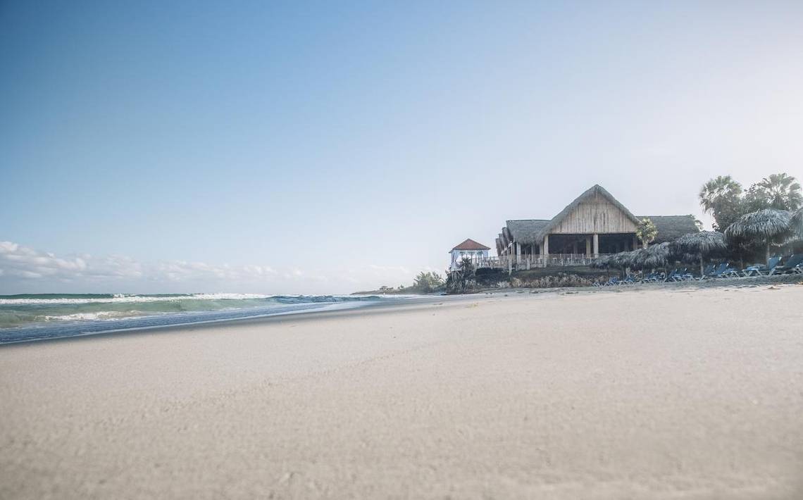 Strand des Iberostar Origin Bella Costa Hotels mit Sonnenliegen und Gebäuden