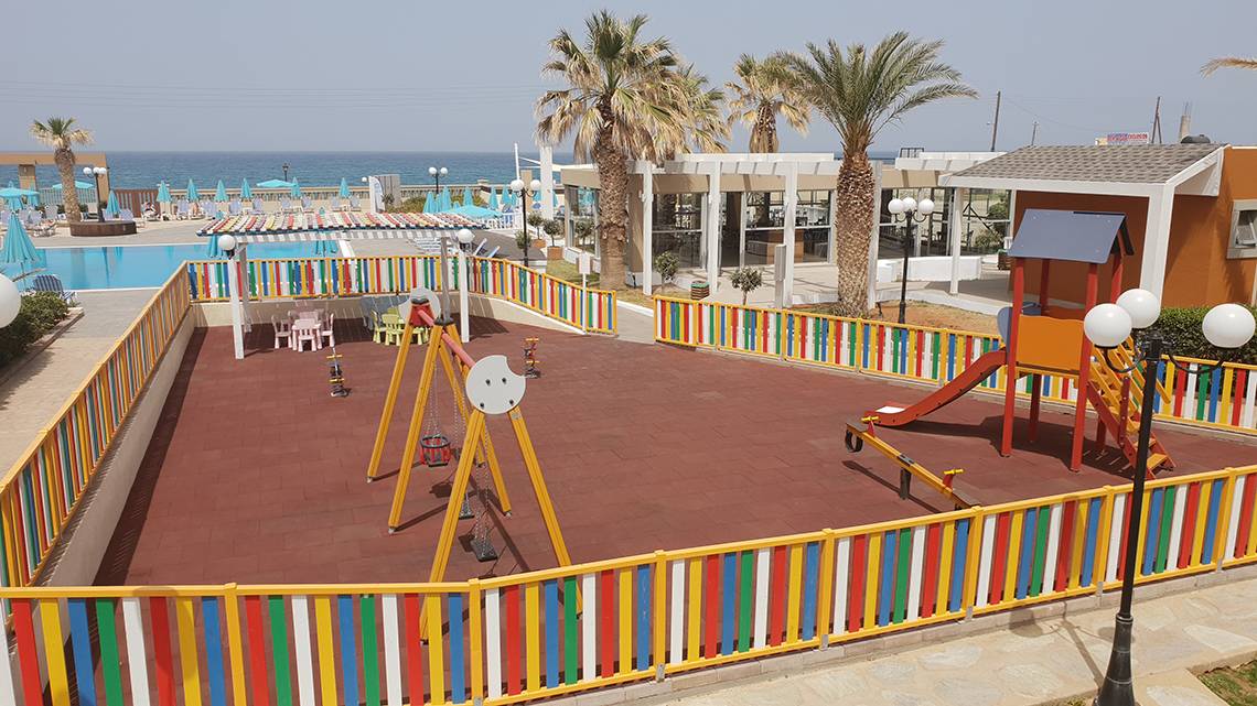 Kinderspielplatz im Freien im Europa Beach Hotel & Spa mit bunten Spielgeräten und Meer im Hintergrund.