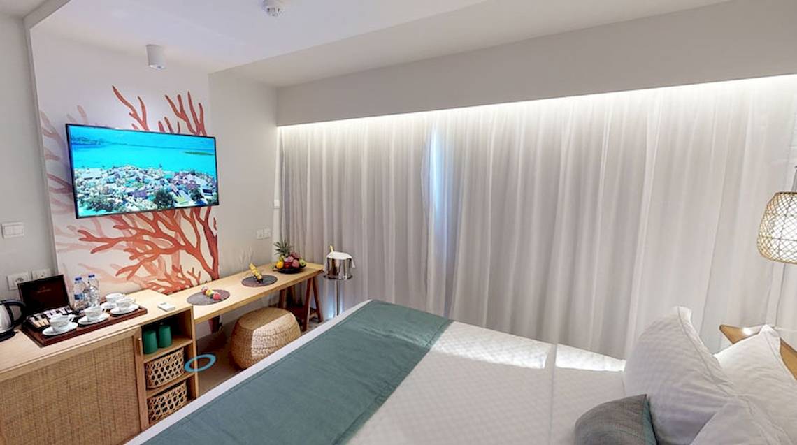 Innenansicht eines Hotelzimmers im Preskil Island Resort mit einem Fernseher und einem Schreibtisch.