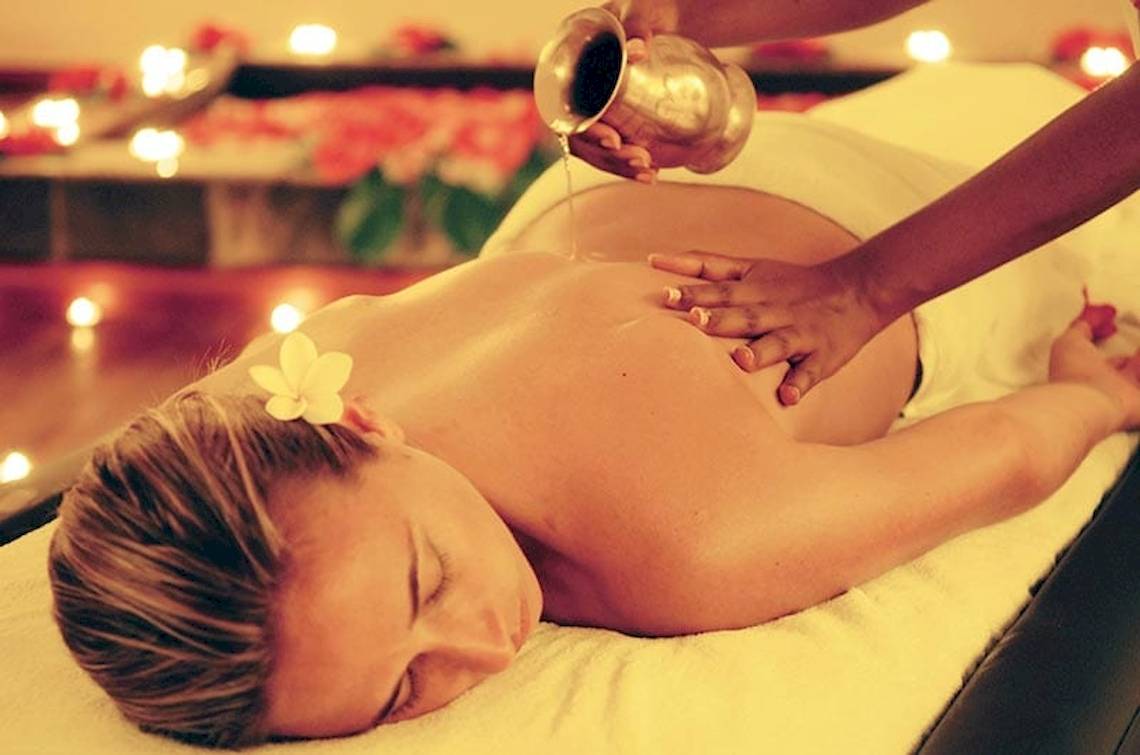 Frau genießt Massage im Preskil Island Resort mit Kerzen und Blumen im Hintergrund