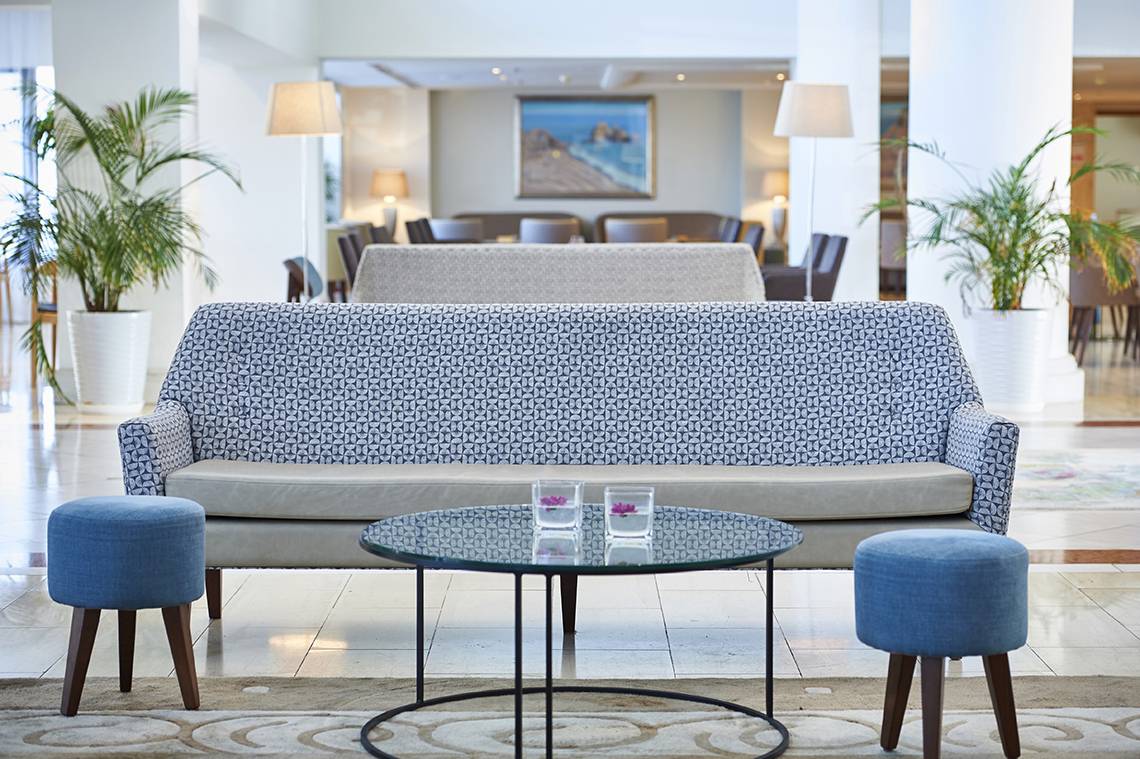 Lobby des Louis Ledra Beach Hotels mit Sofa, Tisch und Pflanzen.