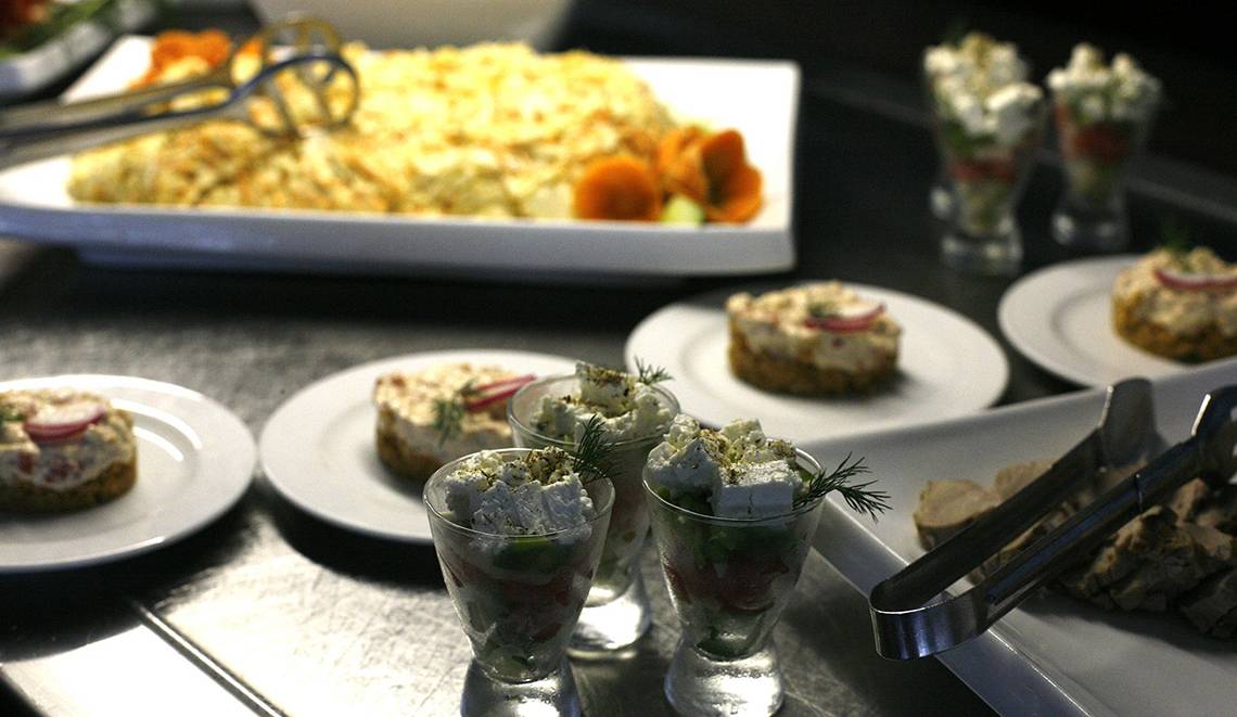 Tisch mit verschiedenen Gerichten im Minos Mare Hotel, darunter Salate und Vorspeisen in Gläsern.