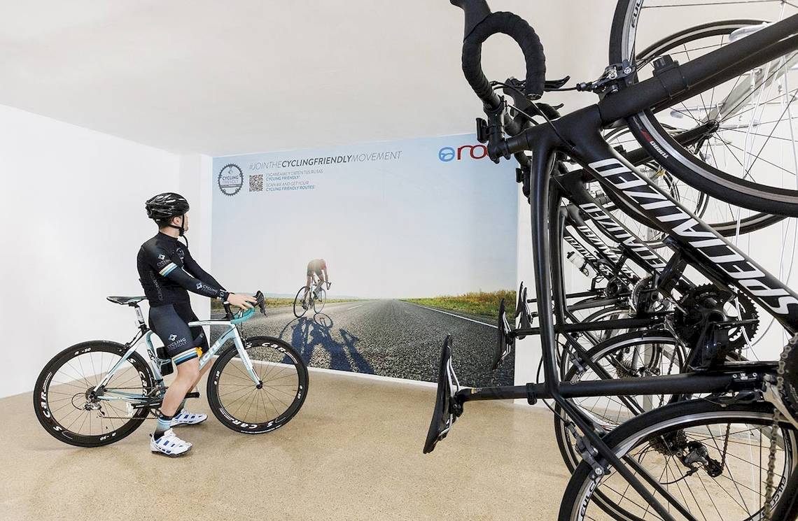 Im Alua Leo Hotel steht ein Fahrrad neben einer Wand mit einem großen Bild von Radfahrern.