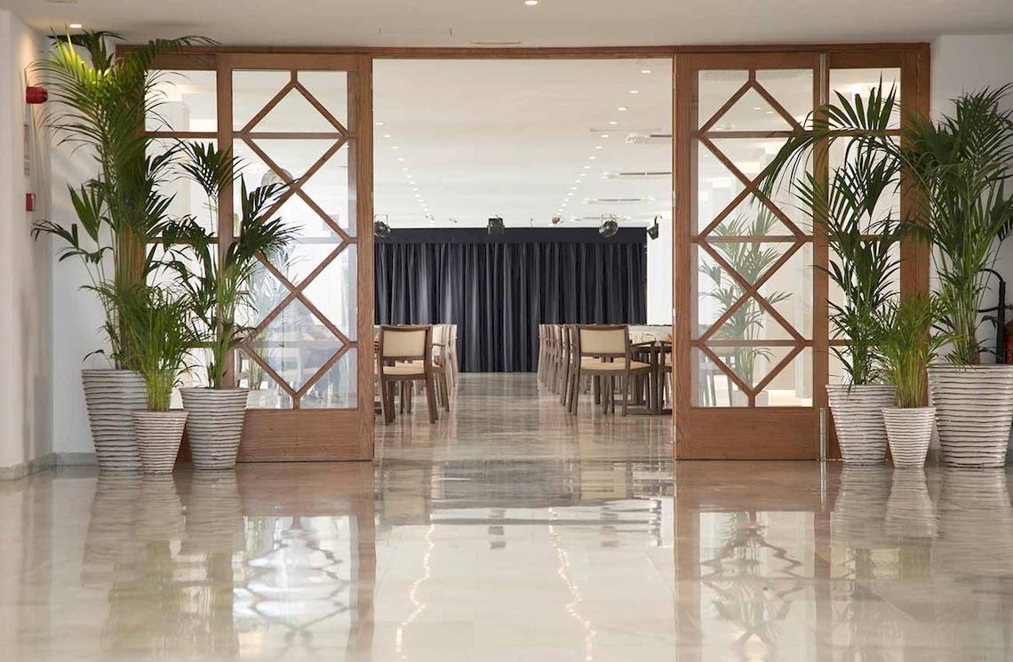 Eingangsbereich des Alua Leo Hotels mit Palmen und gefliestem Boden
