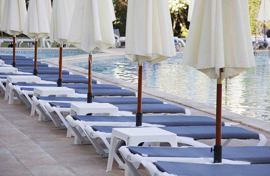 Reihe von weißen und blauen Liegestühlen am Pool des Alua Leo Hotels