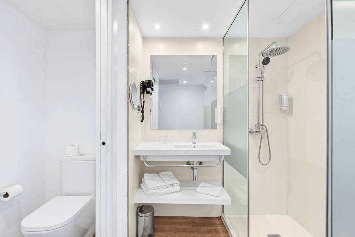 Ein Badezimmer im Alua Leo Hotel mit einer Dusche, Waschbecken und Toilette.
