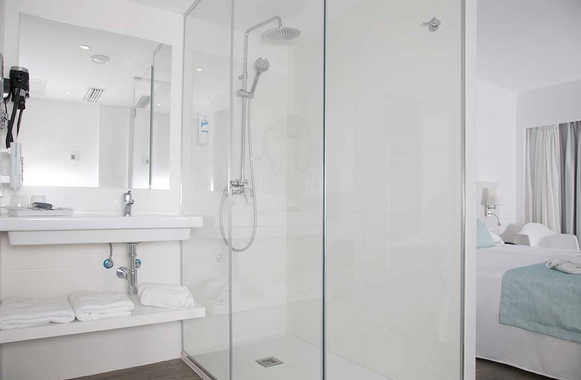 Badezimmer im Alua Leo Hotel mit Duschkabine, Waschbecken und Bett