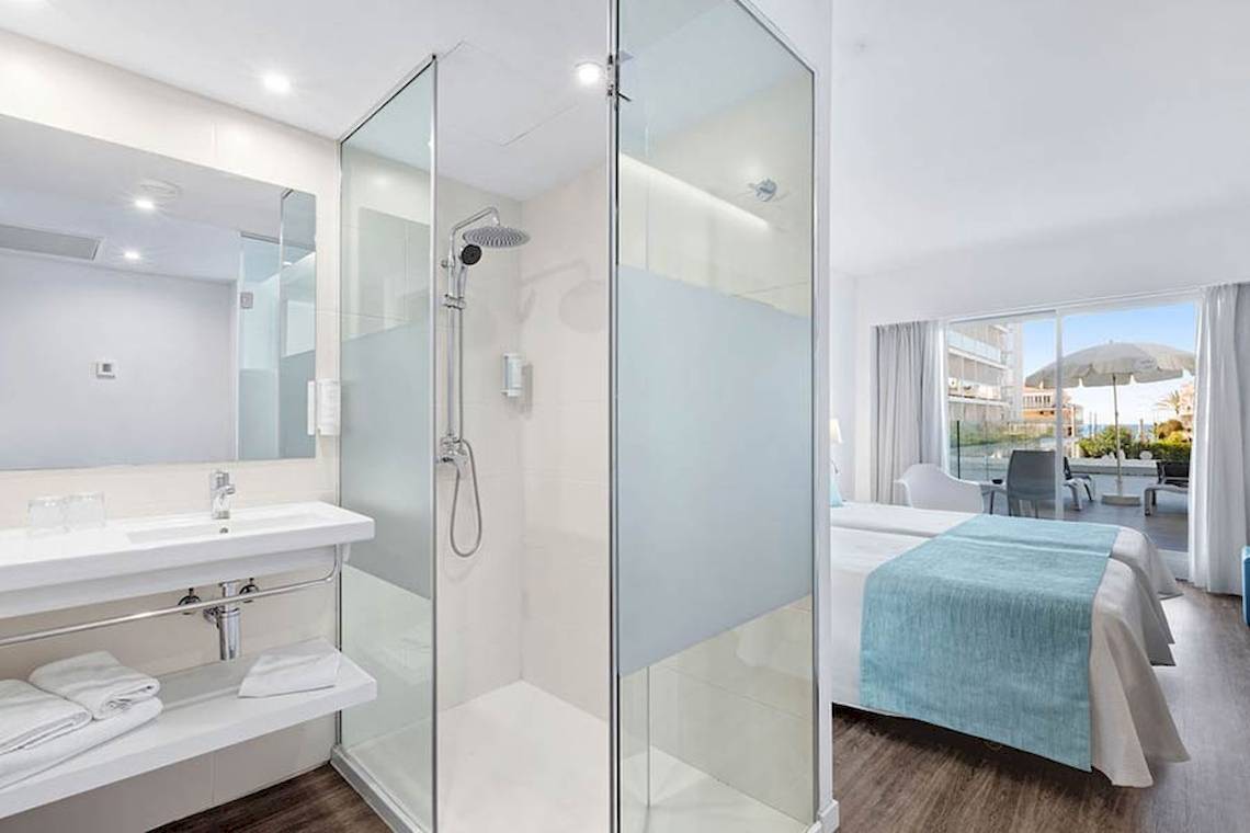Badezimmer im Alua Leo Hotel mit Duschkabine, Waschbecken, Bett und Terrassenzugang.