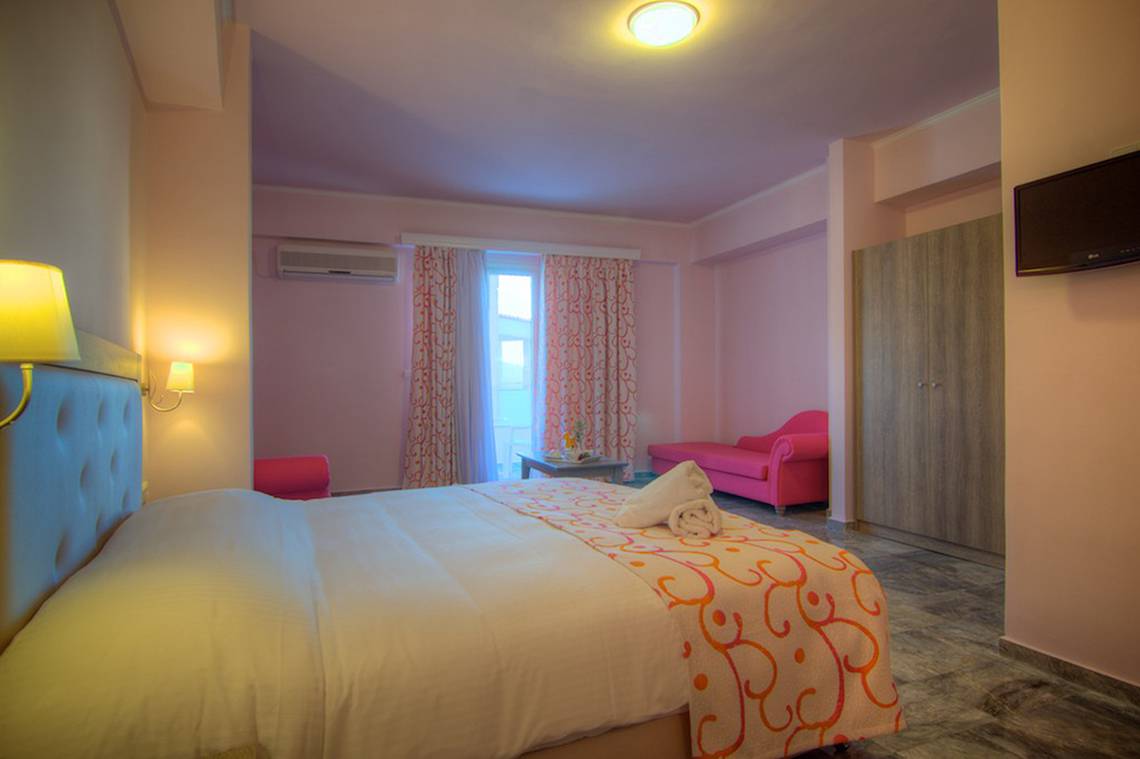 Hotelzimmer im Solimar Dias mit einem Bett, zwei pinken Sesseln, einem Fenster mit Vorhängen und einer Lampe.
