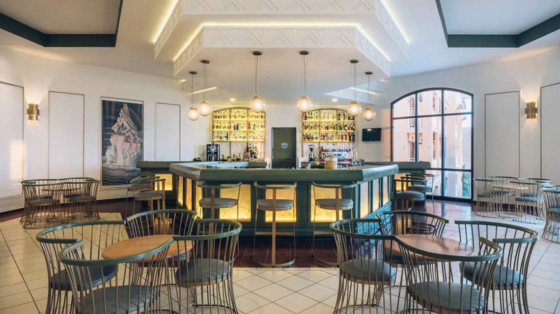 Bar im Iberostar Laguna Azul Hotel mit grüner Theke, hängenden Lampen und modernen Möbeln.