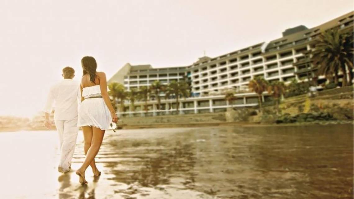 Paar am Strand vor dem Don Gregory Hotel am Meer