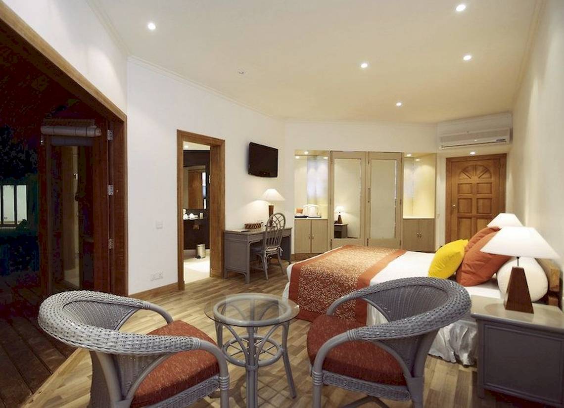 Hotelzimmer im Adaaran Club Rannalhi mit zwei Sessel, Schreibtisch, Bett und Fernseher.