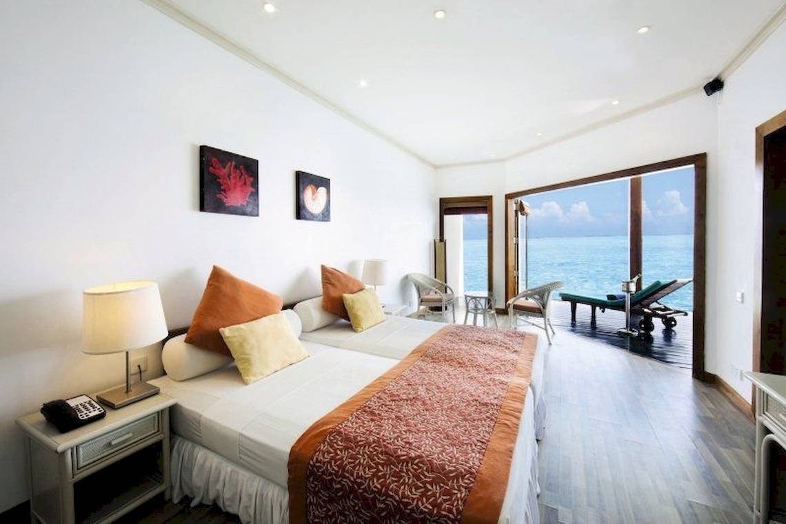Hotelzimmer im Adaaran Club Rannalhi mit Meerblick, inklusive zwei Betten, Möbel und Aussicht auf den Ozean.