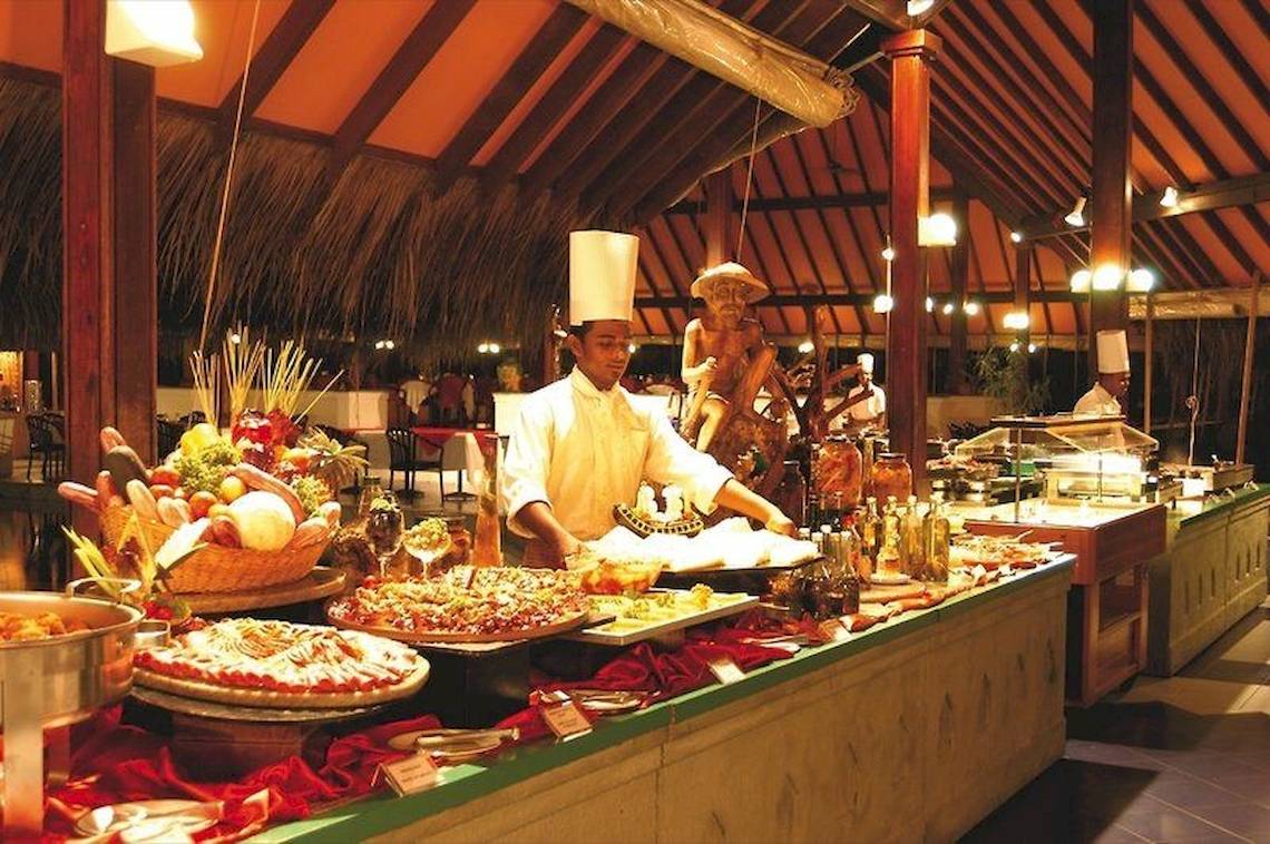 Buffet im Hotel Adaaran Club Rannalhi mit verschiedenen Gerichten und einem Koch, der serviert.