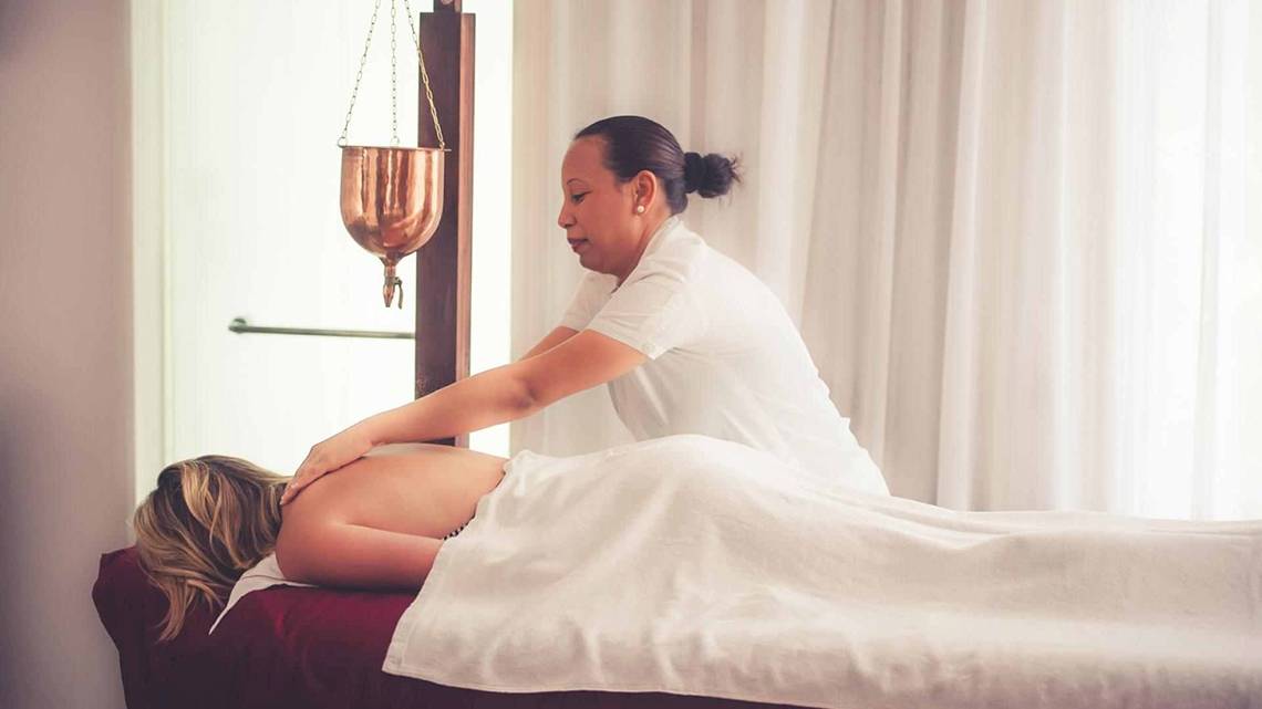 Massagebehandlung im Sugar Beach Mauritius Hotel mit Therapeutin, die Rückenmassage gibt.