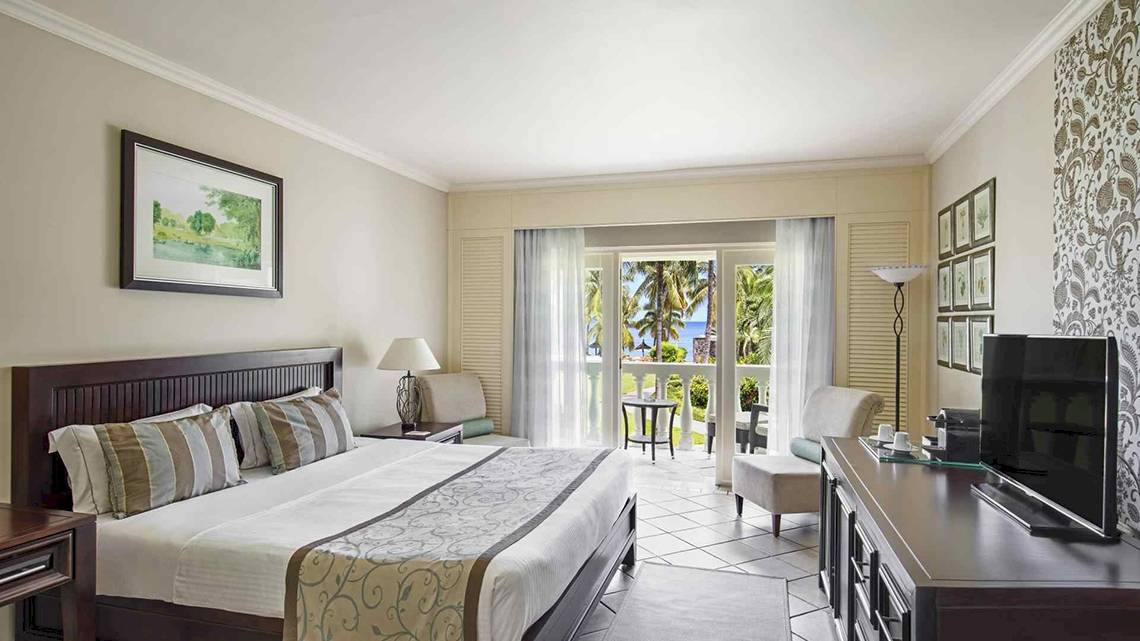 Hotelzimmer im Sugar Beach Mauritius mit Blick auf den Ozean und Möbeln.