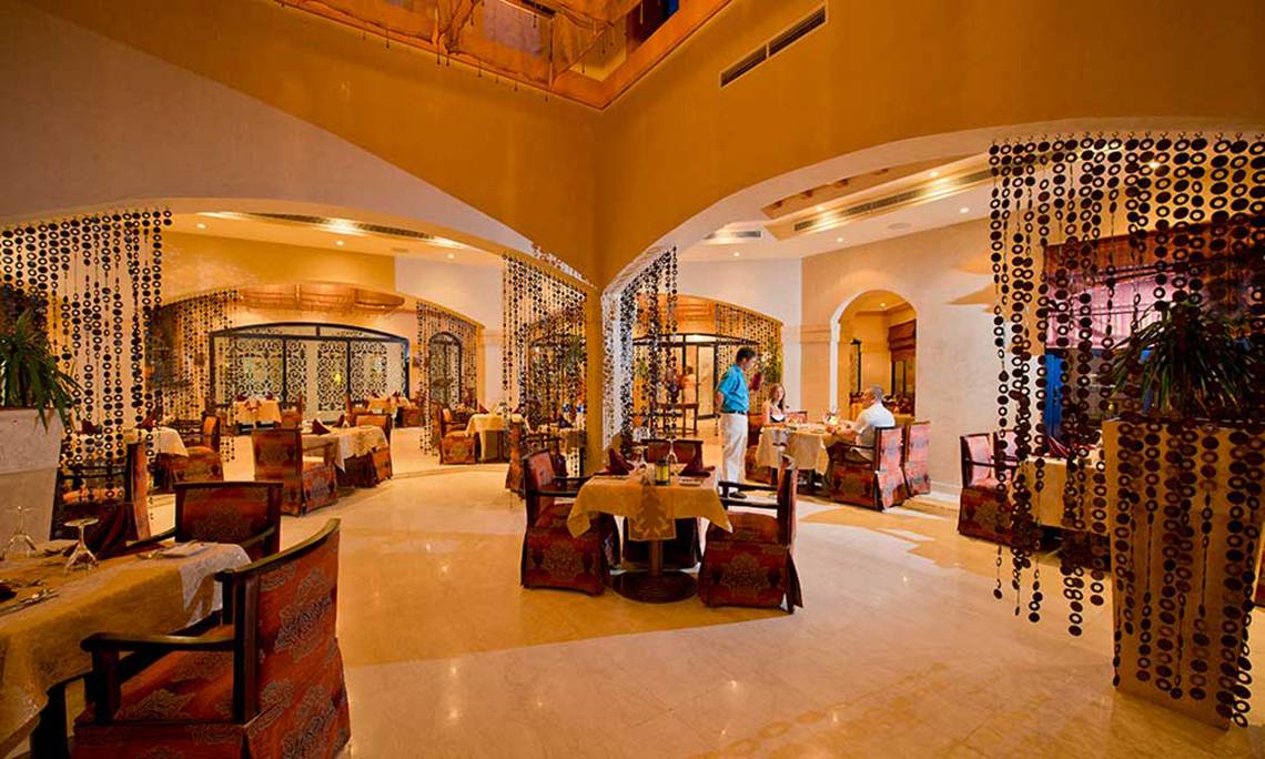 Innenbereich des Amphoras Beach Hotel Restaurants mit runden Tischen, Stühlen und Dekor.