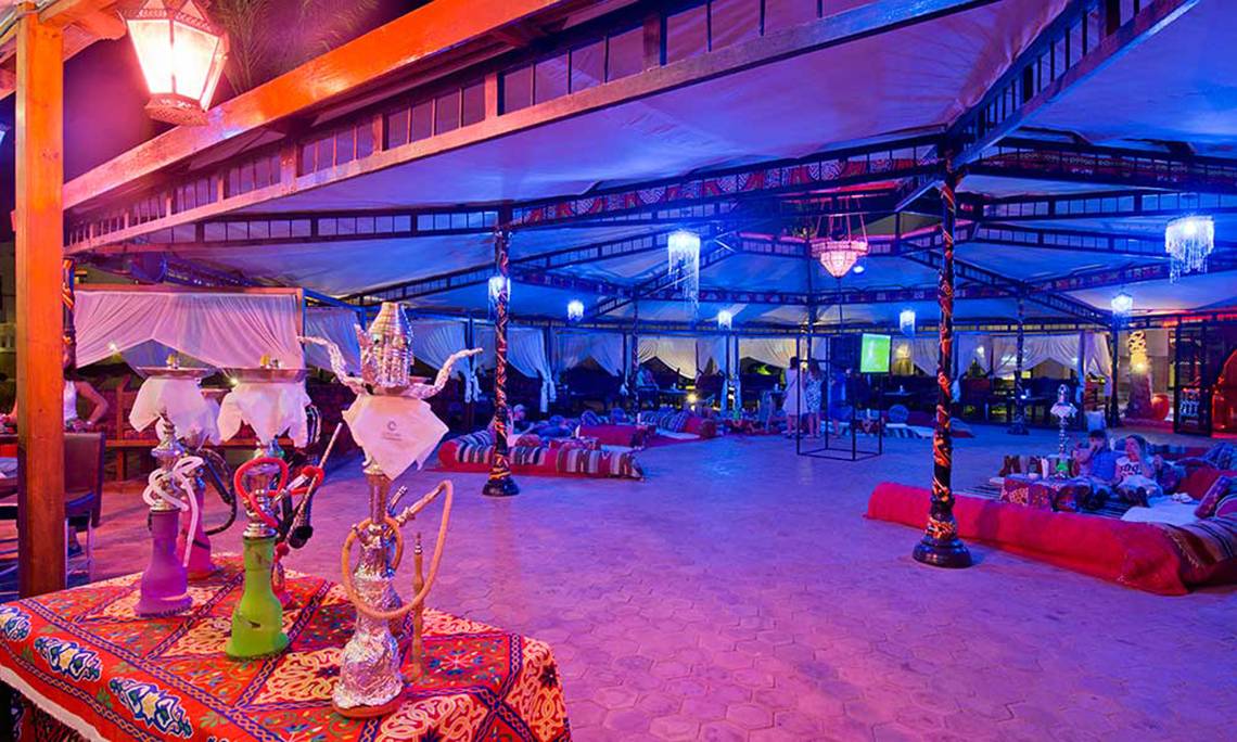 Loungebereich im Amphoras Beach Hotel mit bunten Lichtern, Wasserpfeifen und Liegen.