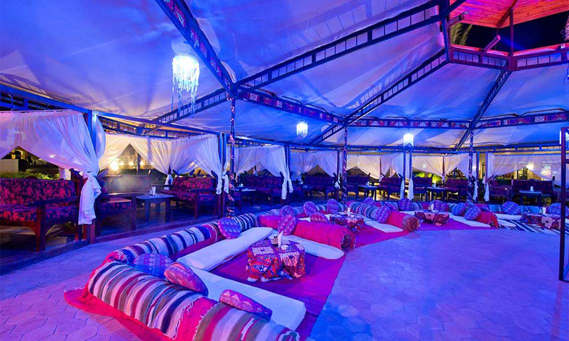 Loungebereich im Amphoras Beach Hotel mit blauer Beleuchtung, weichen Sitzgelegenheiten und Tischchen.