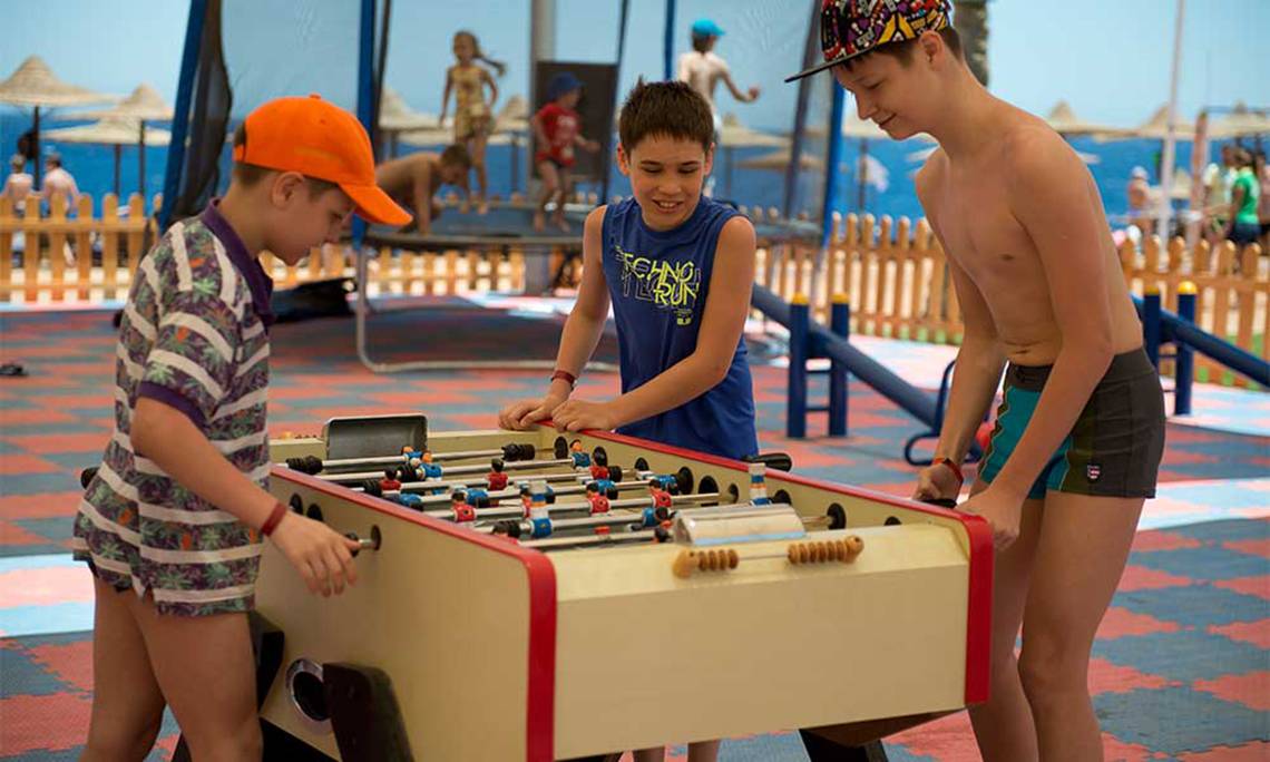 Drei Jungen spielen Tischfußball im Amphoras Beach Hotel.