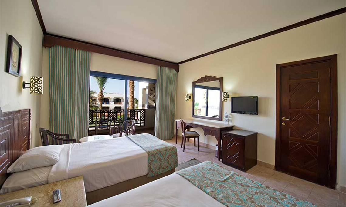Doppelzimmer im Amphoras Beach Hotel mit zwei Betten, Balkon und Fernseher.