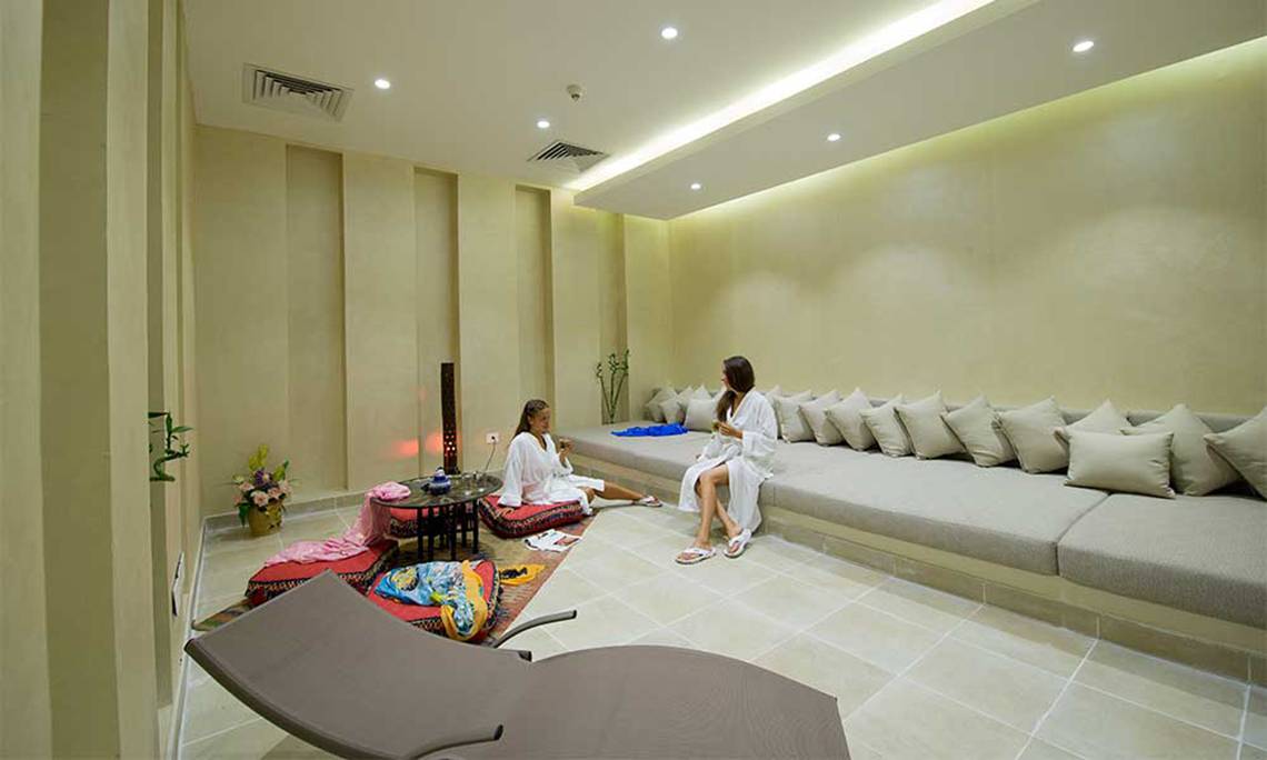 Zwei Frauen im weißen Bademantel sitzen auf Kissen im Amphoras Beach Hotel Lounge