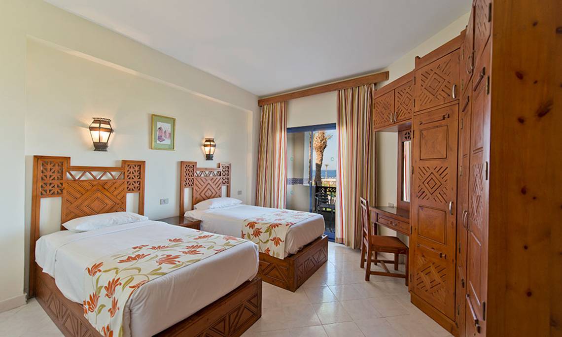 Doppelzimmer im Amphoras Beach Hotel mit zwei Betten, Holzmöbeln und Meerblick.