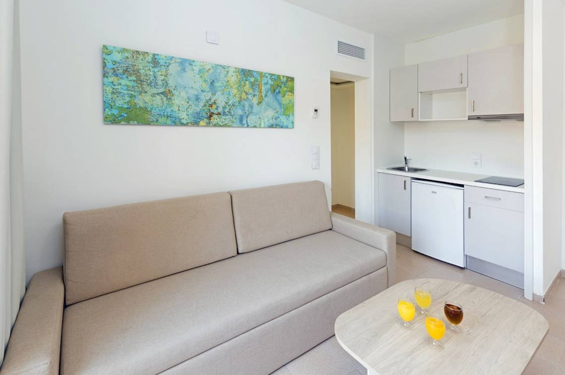 Wohnbereich des HSM Club Torre Blanca mit Sofa, Couchtisch und Küche