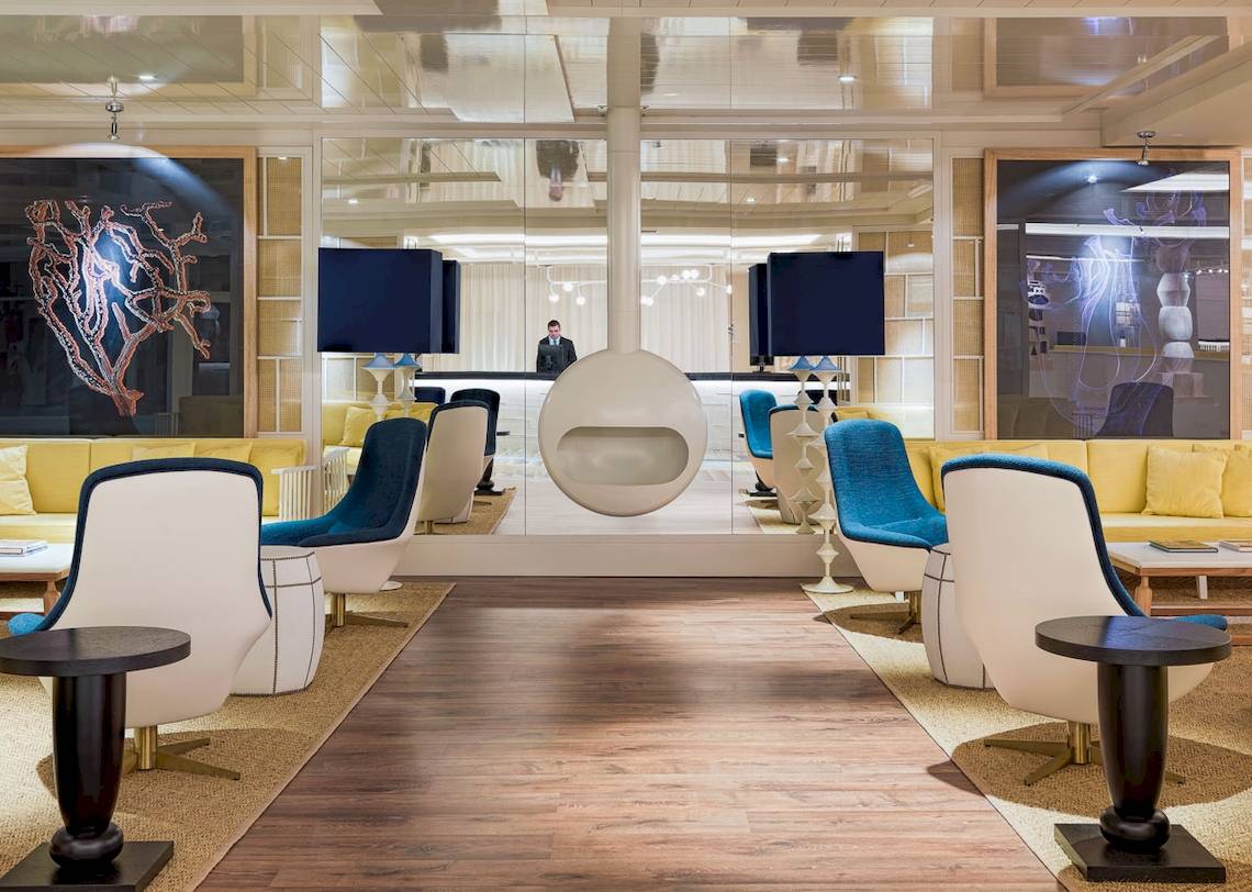 Lobby des H10 Las Palmeras Hotels mit moderner Einrichtung, Spiegeln und Kunstwerken.