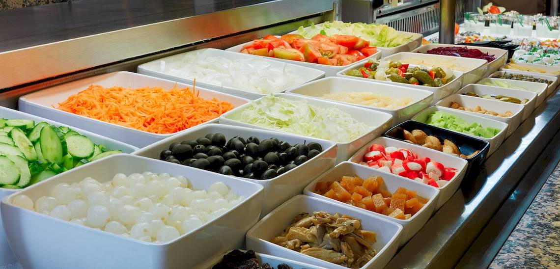 Buffet mit verschiedenen Gemüse- und Obstsorten, darunter Tomaten, Gurken, Oliven, Datteln und mehr.