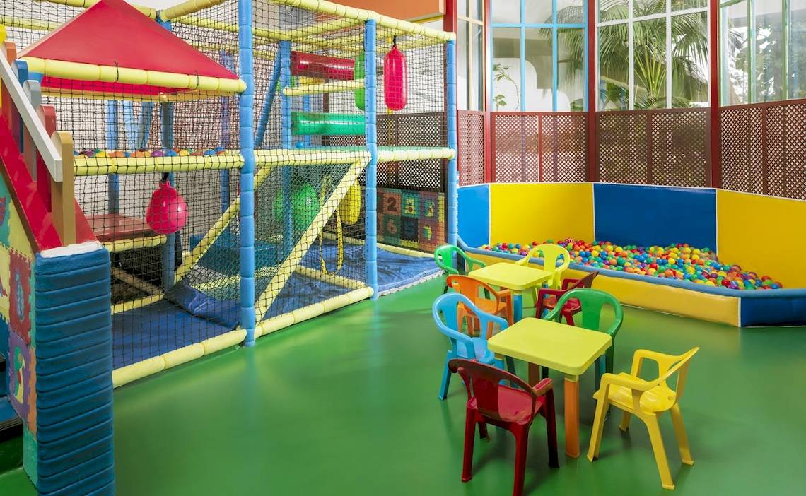 Kinderspielplatz im H10 Las Palmeras mit Klettergerüst, Ballgrube und bunten Tischen und Stühlen.