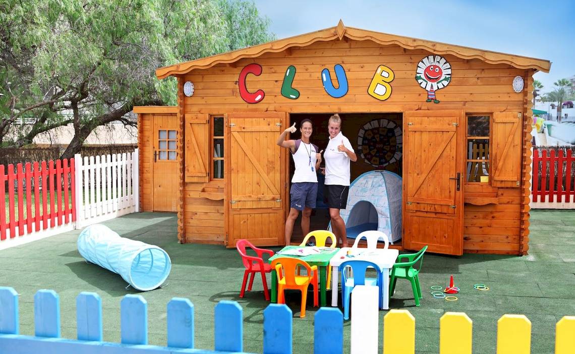 Zwei Frauen vor einem Clubhaus von H10 Las Palmeras mit bunten Spielsachen und Tischen.