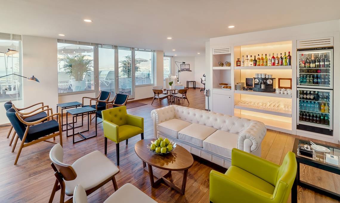 Lobby-Lounge des H10 Las Palmeras Hotels mit weißen Ledersofa, farbigen Sesseln und modernem Design.