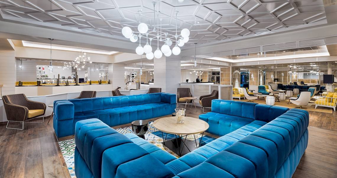Lobby des H10 Las Palmeras Hotels mit blauen Sofas, Kronleuchter und modernem Design.