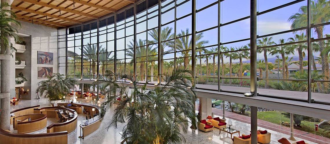 Lobby des Tabaiba Princess Hotels mit großen Fenstern, Palmen und modernen Möbeln.