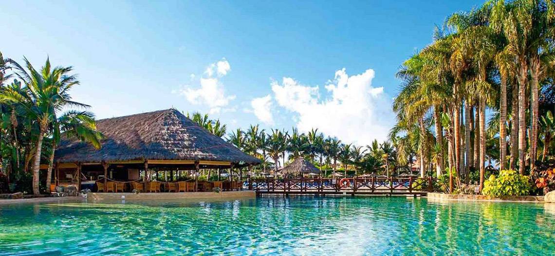 Außenbereich des Tabaiba Princess Hotels mit einem Schwimmbad, einer Brücke und einer Bar.