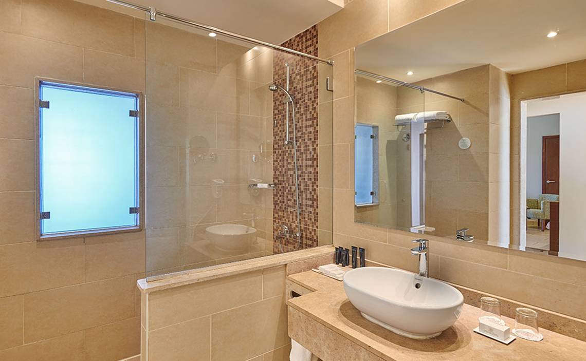 Badezimmer im Steigenberger Aqua Magic Hotel mit großer Glasdusche, Waschbecken und Spiegel.
