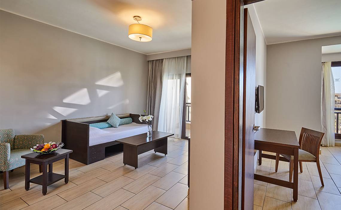 Zimmer im Steigenberger Aqua Magic Hotel mit einem Bett, einem Tisch, einem Stuhl und einer Lampe.