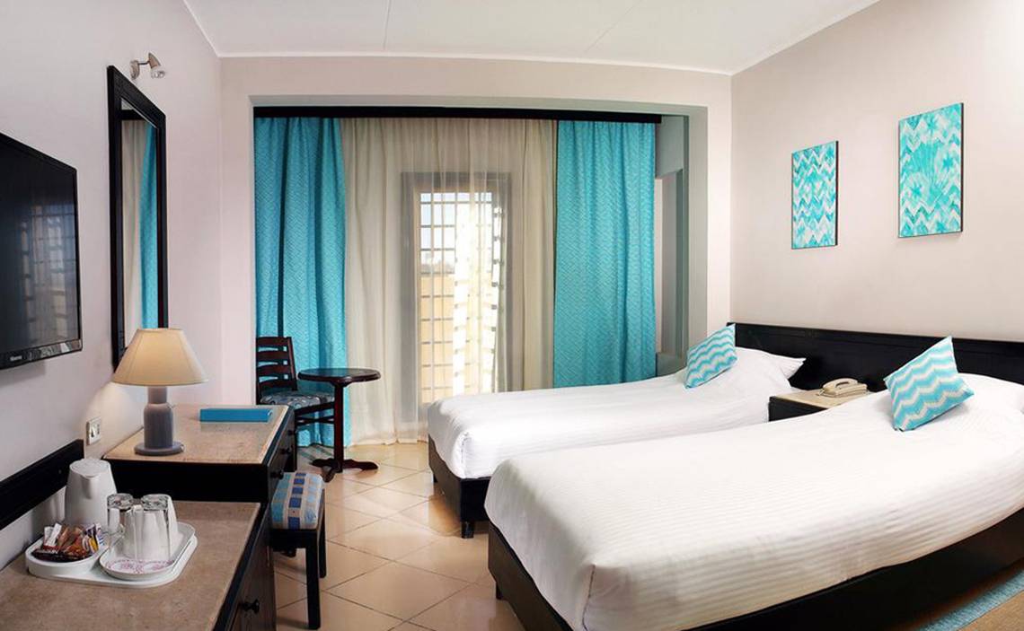 Doppelzimmer im Steigenberger Aqua Magic Hotel mit zwei Betten, Fernseher, Schreibtisch und Dekoration.