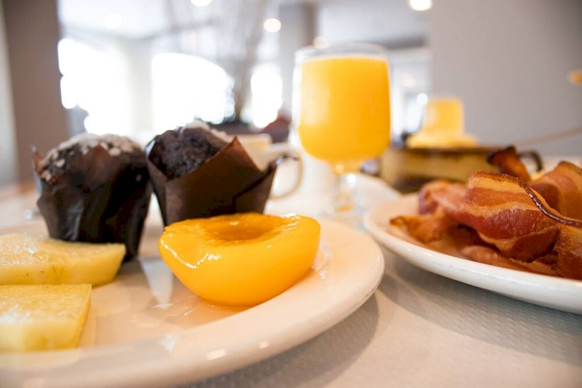 Frühstücksbuffet im Calypso Hotel mit Muffins, Pfirsich, Orangensaft und Speck.