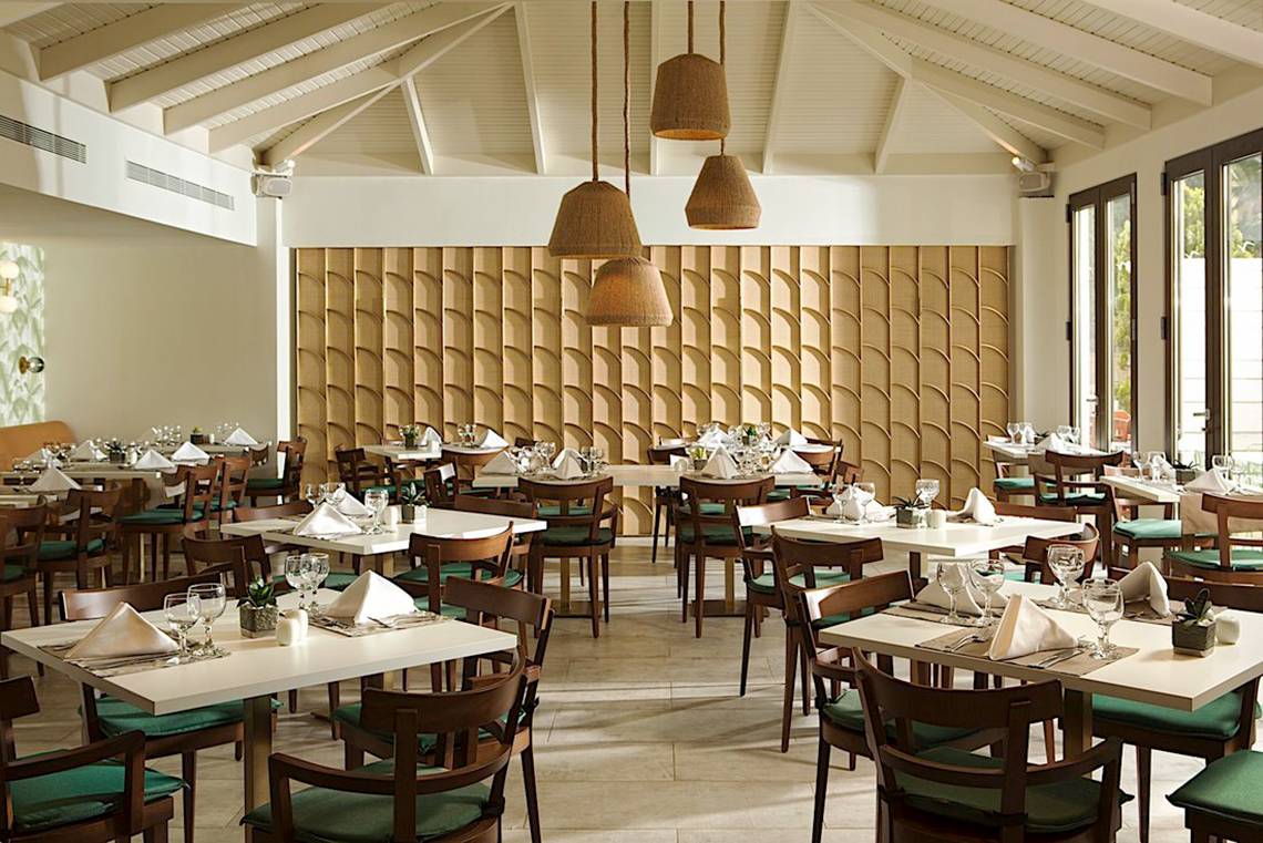 Innenbereich eines Restaurants im Cretan Malia Park Hotel mit runden Holzlampen und geometrischen Wandverkleidungen.